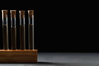 Photo of Test tubes with liquid in stand on grey table. Space for text