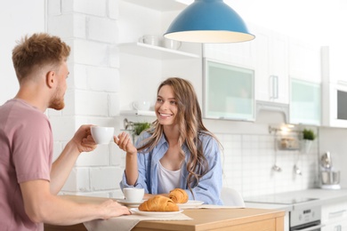 Happy young couple having breakfast at table in kitchen