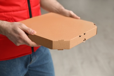 Man with pizza box indoors, closeup. Food delivery service