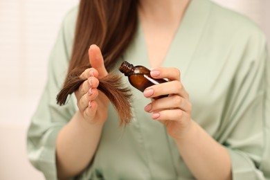 Photo of Woman applying oil hair mask indoors, closeup