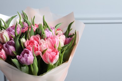 Photo of Bouquet of beautiful tulips near grey wall, closeup. Space for text