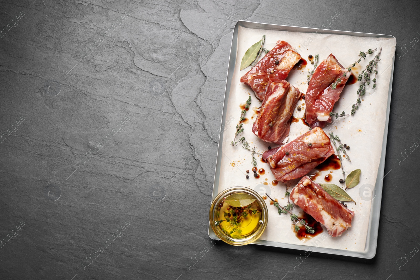Photo of Raw marinated ribs on black table, top view. Space for text