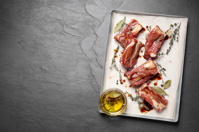 Photo of Raw marinated ribs on black table, top view. Space for text