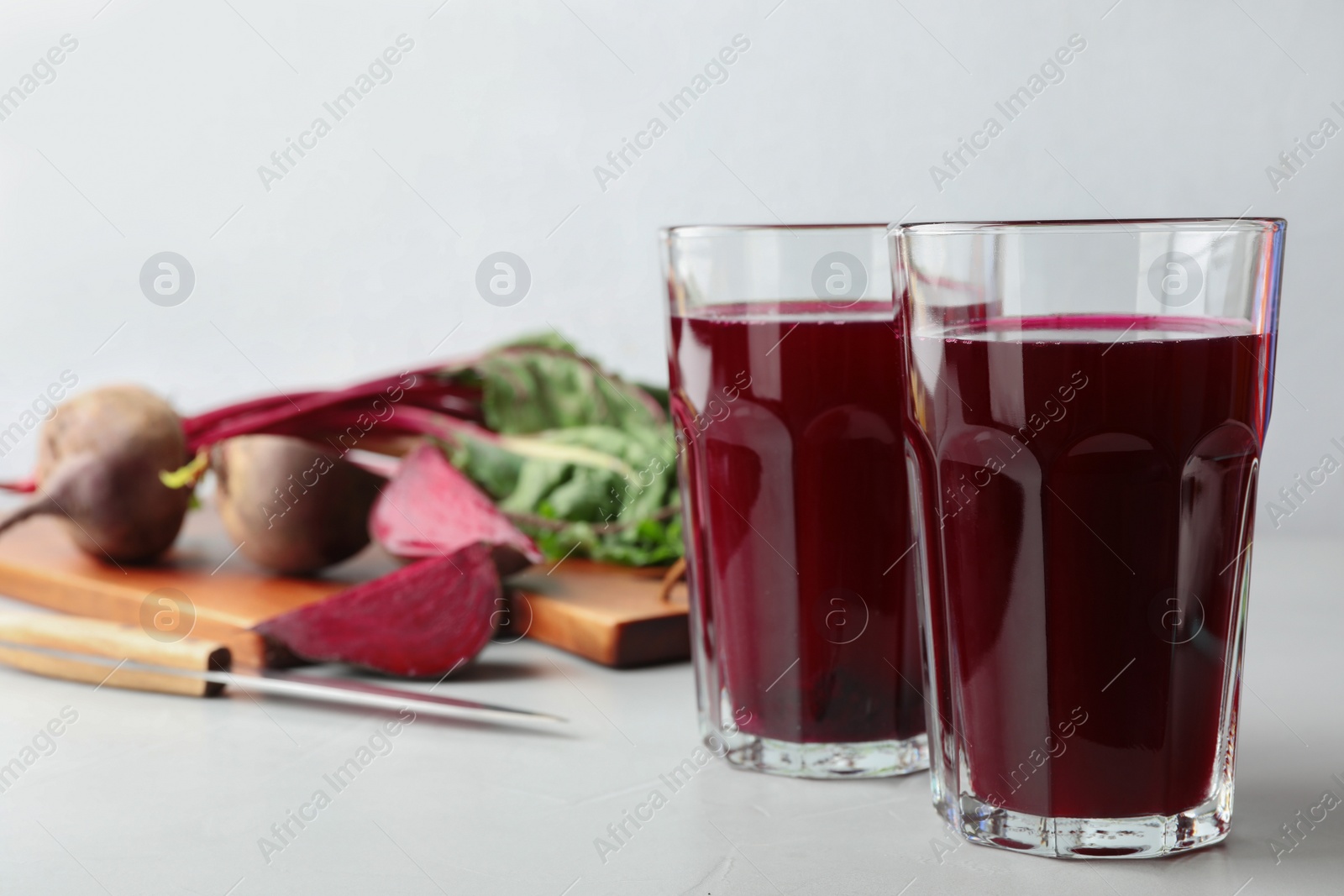 Photo of Glasses of beet juice on light table. Space for text