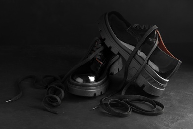 Pair of stylish shoes with laces on black background