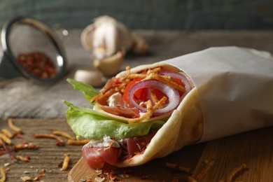 Photo of Delicious pita wrap with prosciutto and vegetables on wooden table, closeup. Space for text