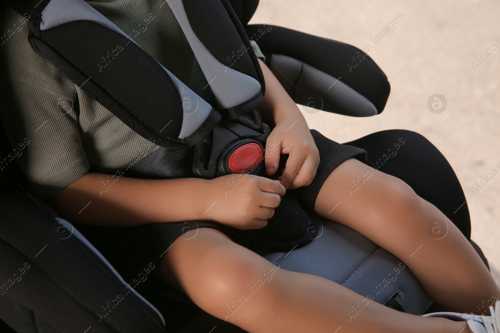 Photo of Little boy fastened with car safety belt in child seat, closeup