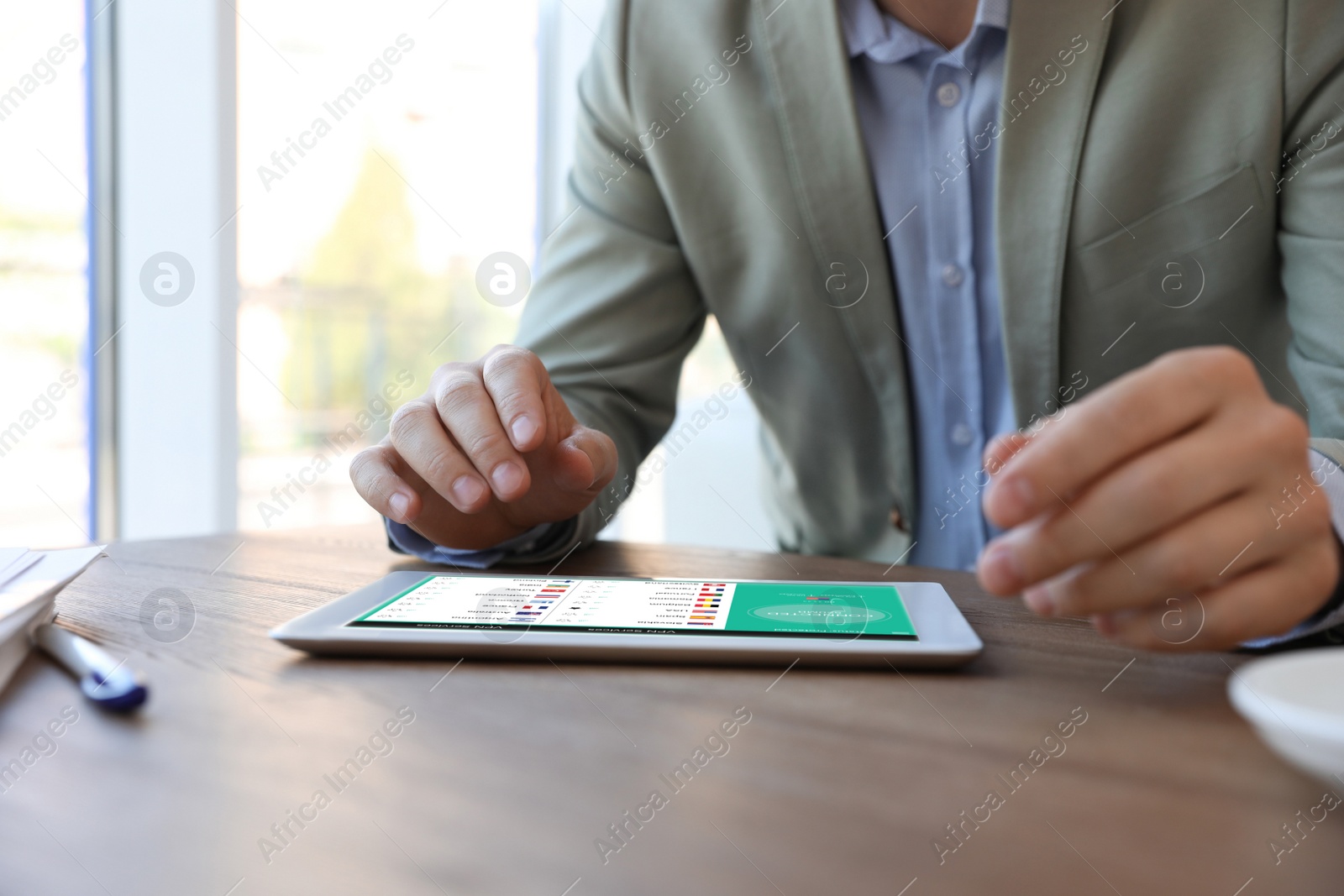 Image of Man using modern tablet with switched on VPN at wooden table in office, closeup