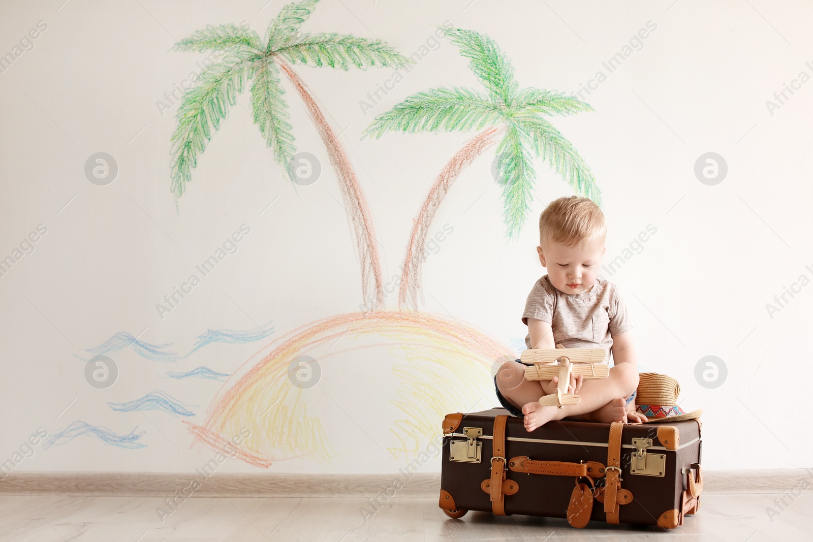 Photo of Adorable little child playing traveler with suitcase indoors