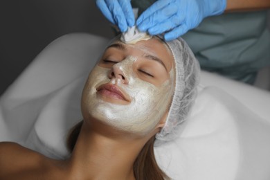 Photo of Cosmetologist removing mask from client's face in spa salon
