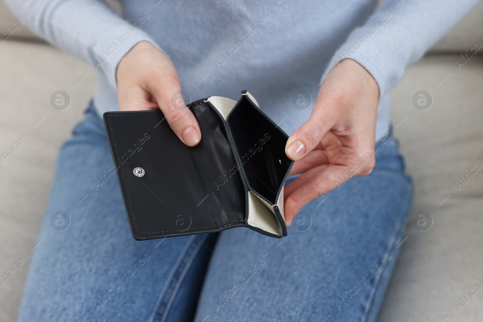 Photo of Woman with empty wallet on sofa indoors, closeup