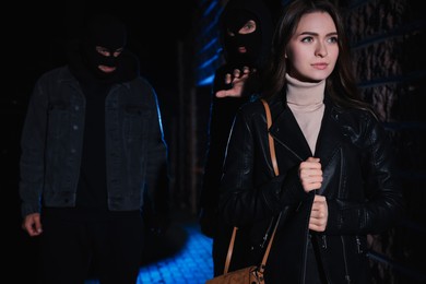 Photo of Men in masks stalking young woman outdoors at night