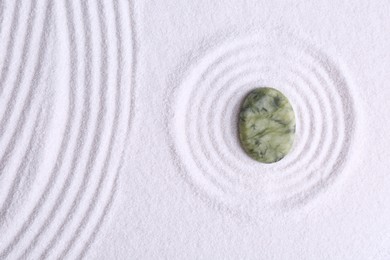 Photo of Zen concept. Stone and pattern on white sand, top view. Space for text