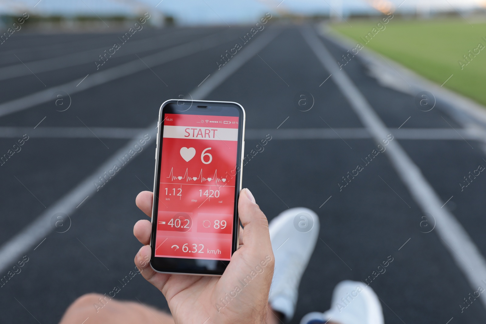 Photo of Man using fitness app on smartphone at stadium, closeup