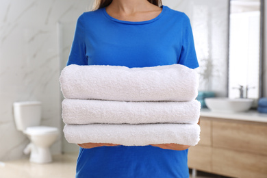 Photo of Woman holding fresh towels in bathroom, closeup