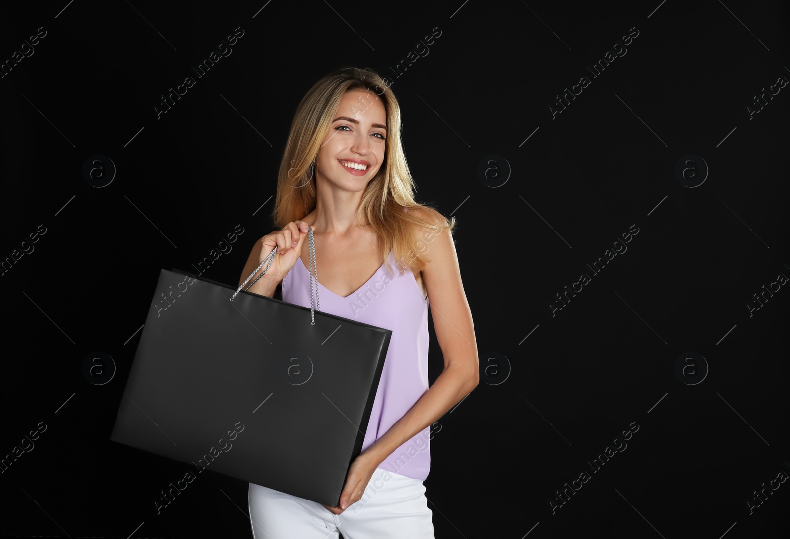 Photo of Happy young woman with shopping bag on dark background, space for text. Black Friday Sale