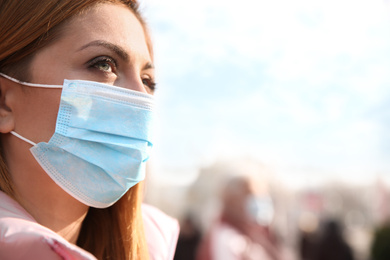 Photo of Woman with medical mask on city street. Virus protection