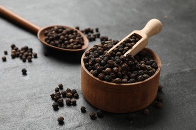 Photo of Aromatic spice. Pepper in bowl and scoop on black table