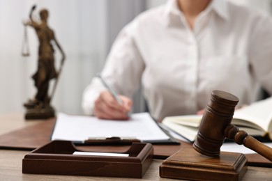 Lawyer working with documents at wooden table in office, focus on gavel