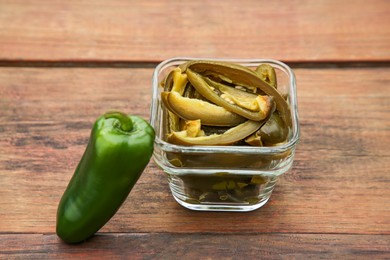 Photo of Fresh and pickled green jalapeno peppers on wooden table, closeup