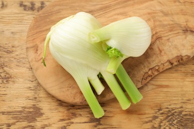 Photo of Fresh raw fennel bulbs on wooden table, top view