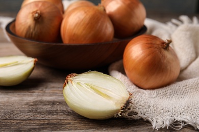 Photo of Cut and whole onions on wooden table