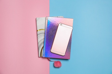 Photo of Modern smartphone and notebooks on color background, top view
