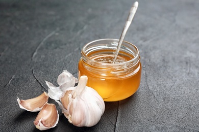 Photo of Jar with honey and garlic for cold on table