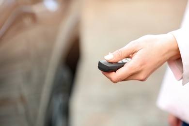 Photo of Closeup view of woman opening car door with remote key. Space for text