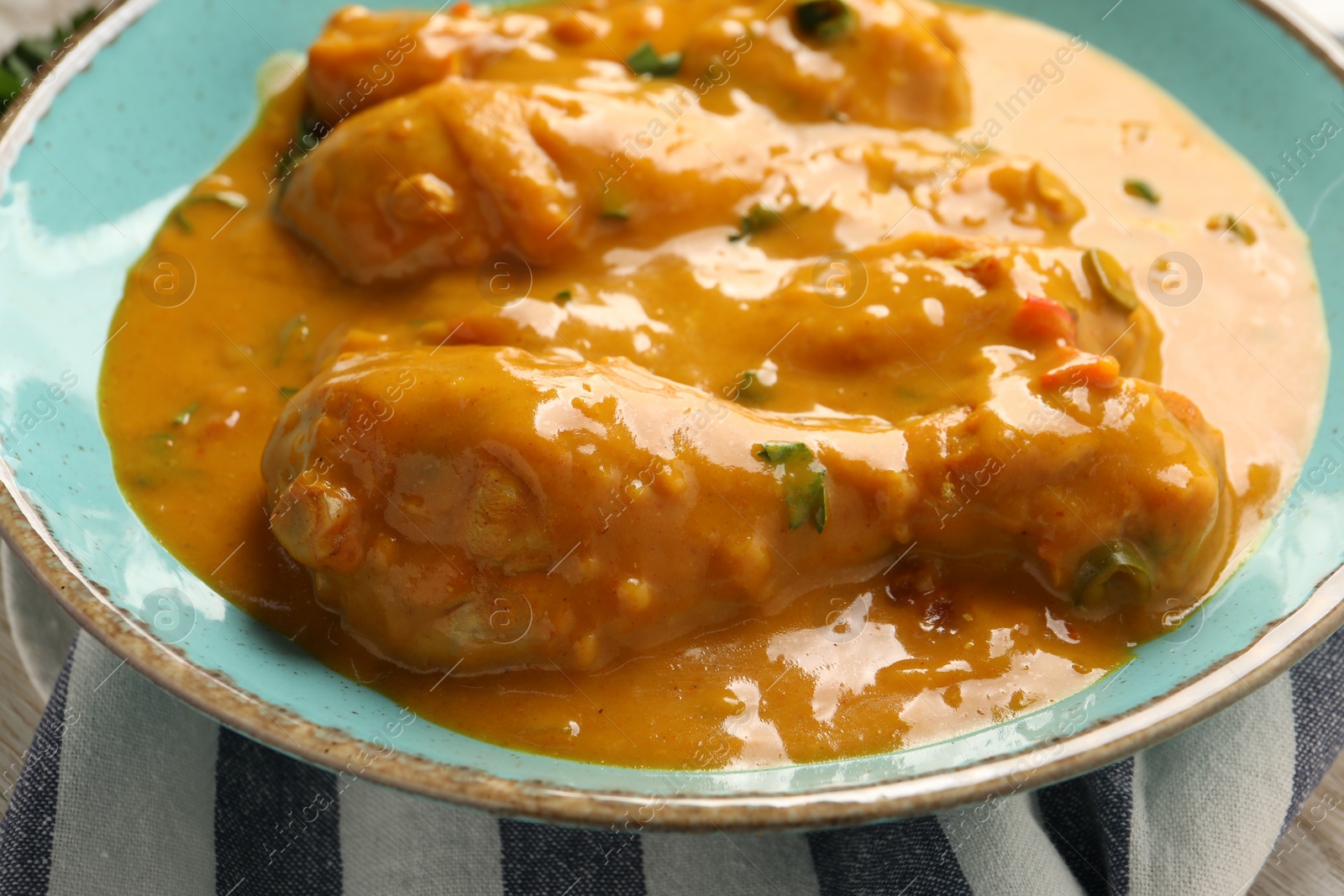Photo of Tasty chicken curry on light blue plate, closeup