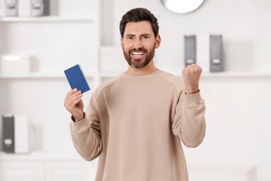 Immigration. Portrait of happy man with passport indoors
