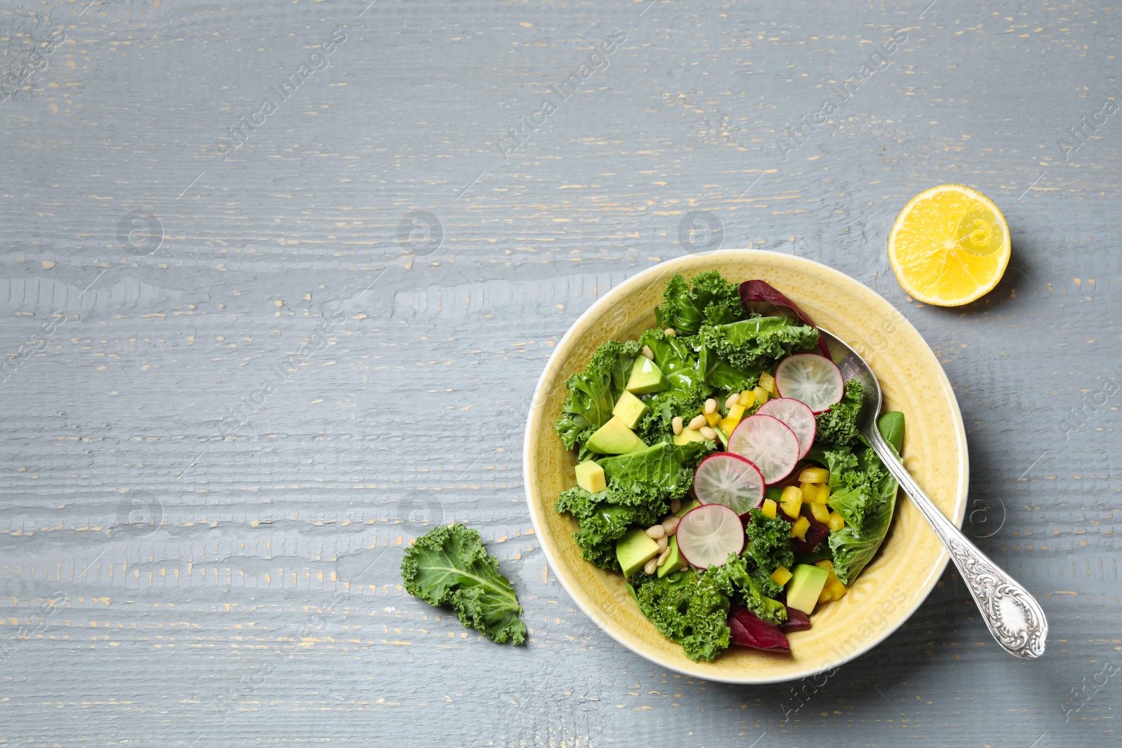 Photo of Delicious kale salad served on grey wooden table, flat lay. Space for text