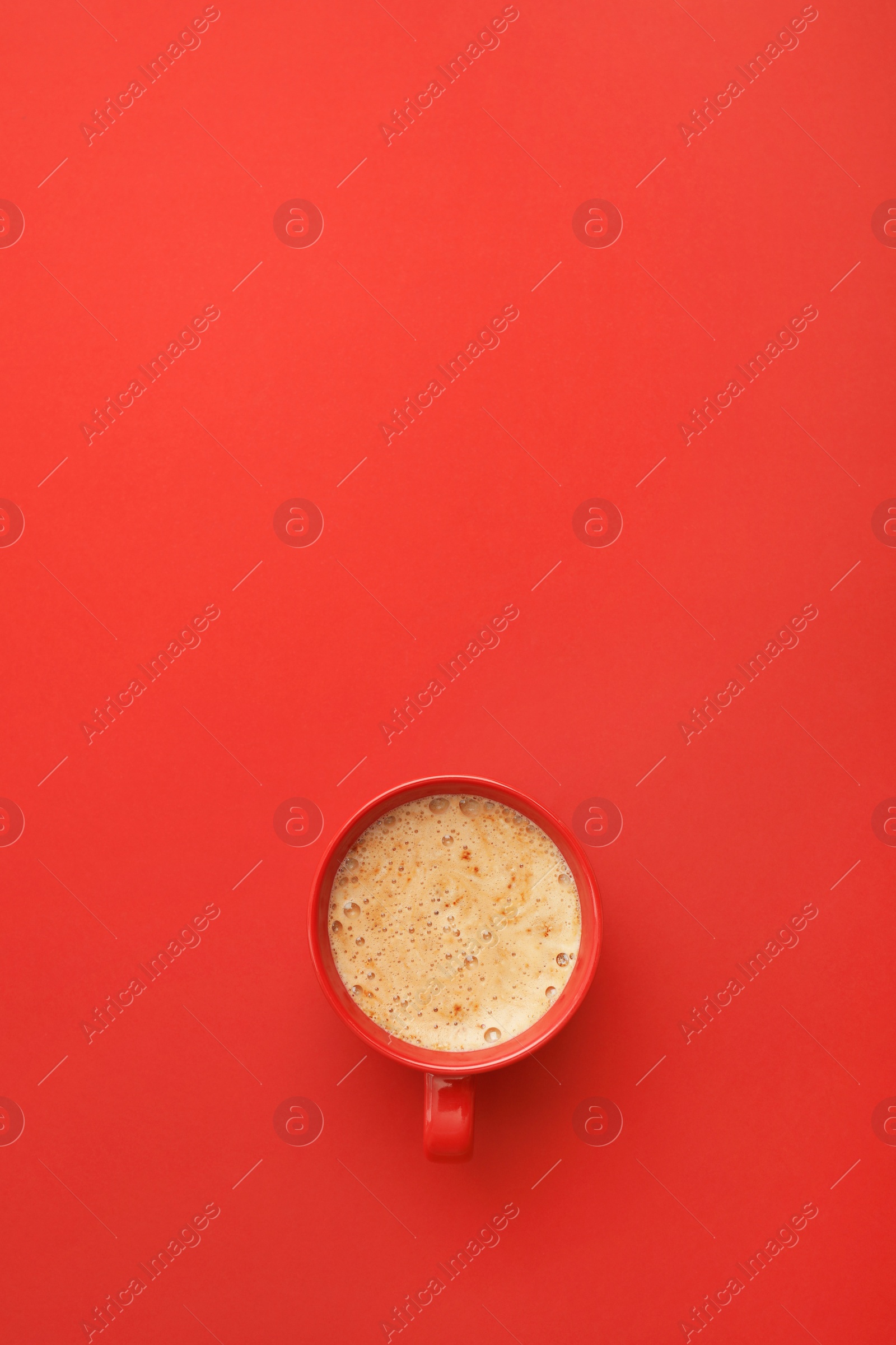 Photo of Cup of coffee on red background, top view. Space for text