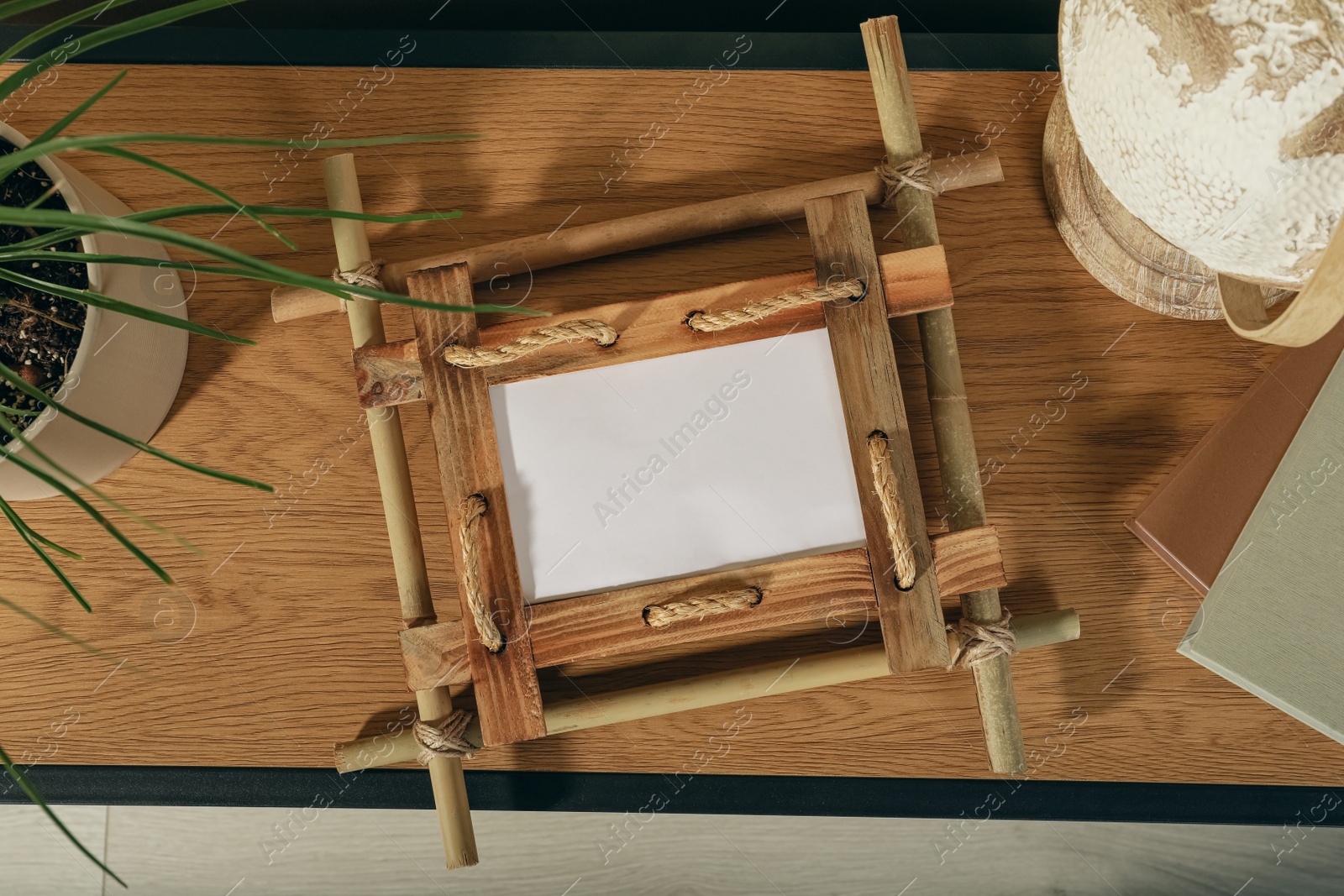 Photo of Bamboo frame, plant and globe on wooden table, top view