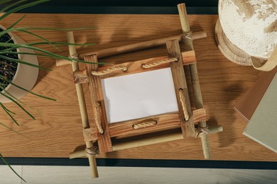 Photo of Bamboo frame, plant and globe on wooden table, top view