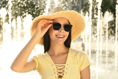 Photo of Beautiful young woman wearing stylish sunglasses outdoors