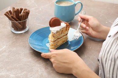 Photo of Woman eating delicious homemade cake with caramel sauce at table