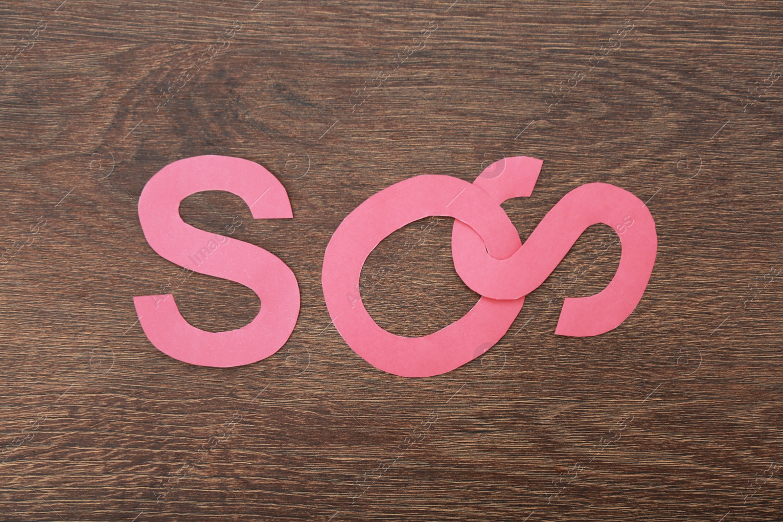 Photo of Abbreviation SOS made of paper letters on wooden background, top view