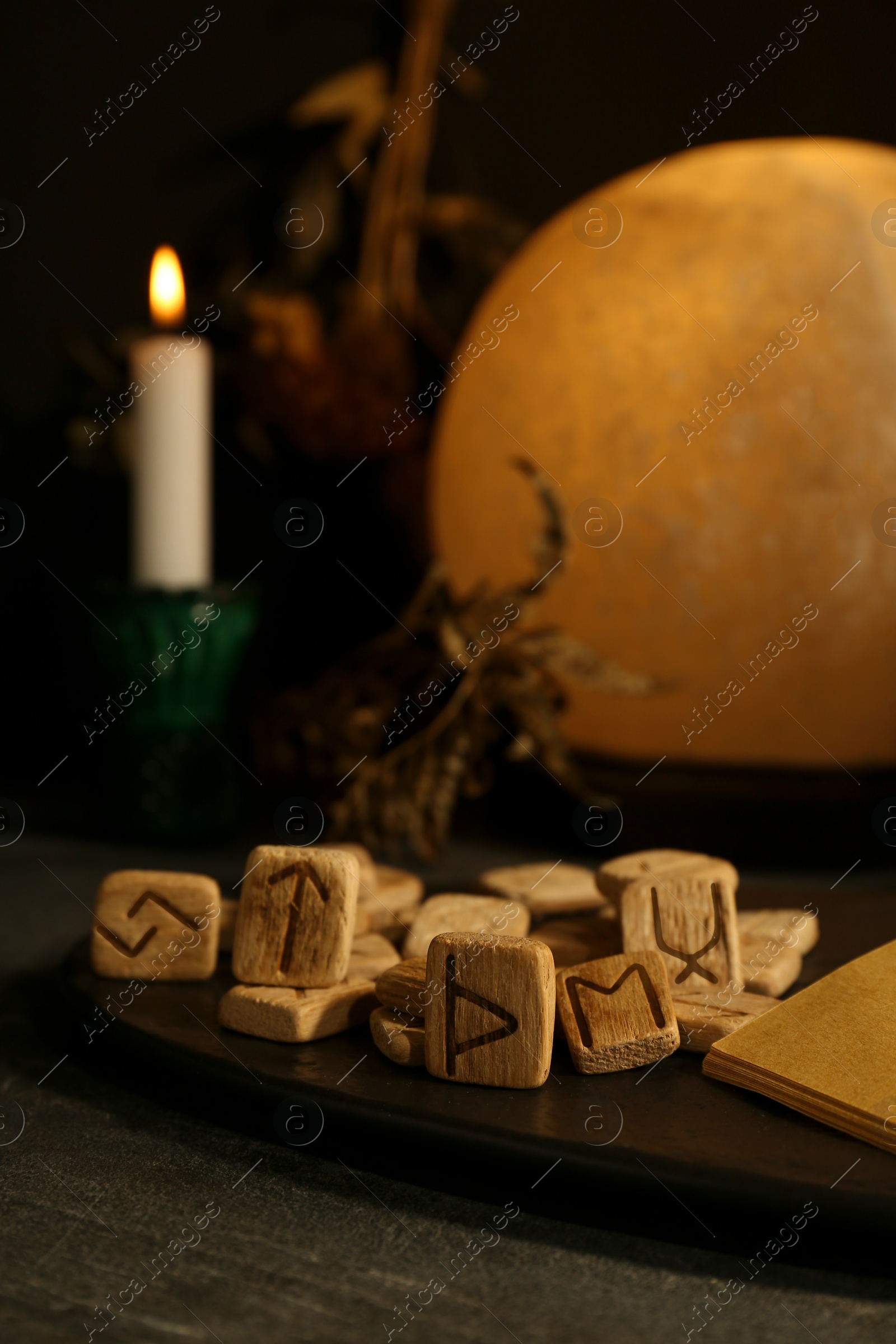 Photo of Composition with wooden runes and old book on black table