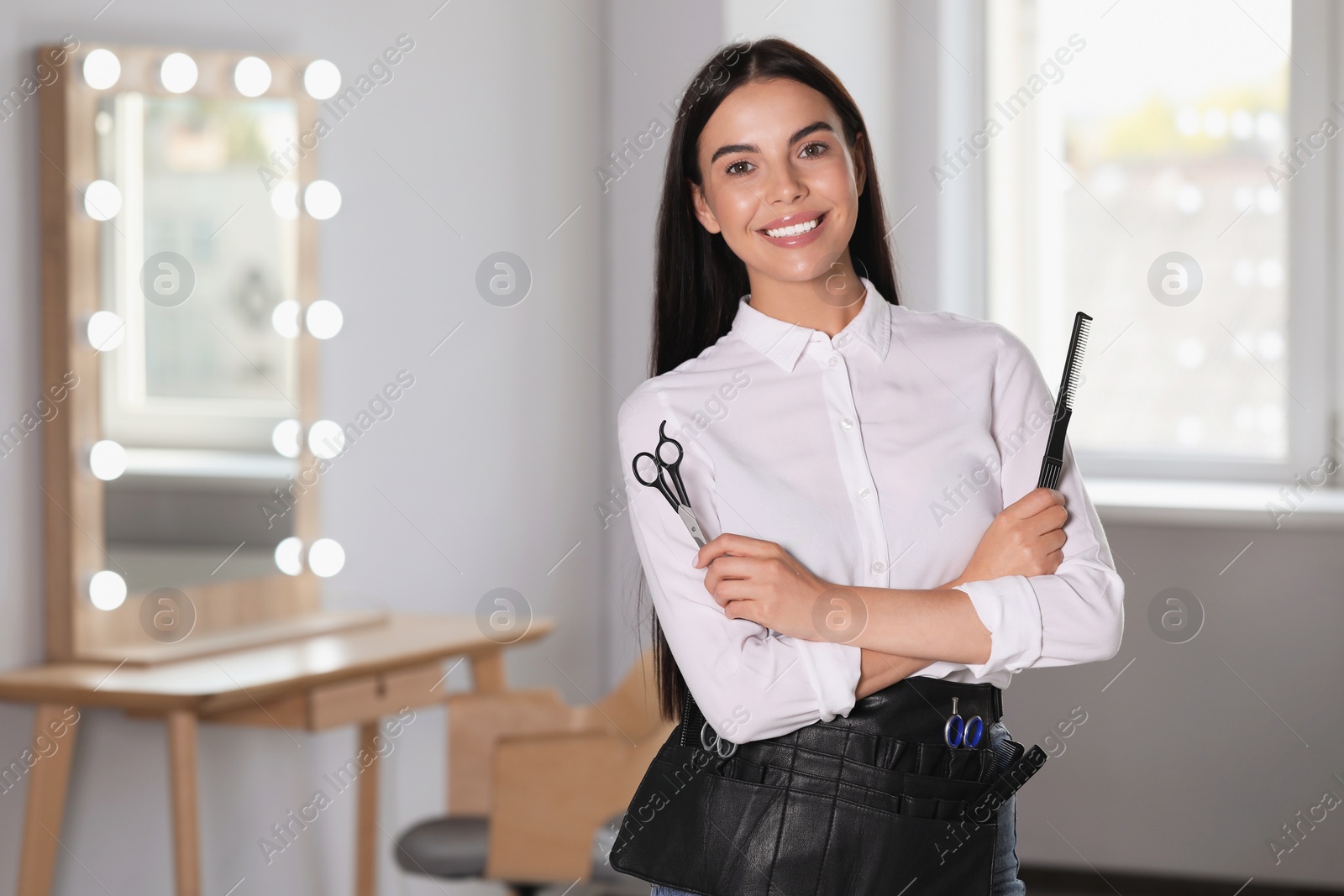 Photo of Portrait of happy hairdresser with professional tools in beauty salon, space for text