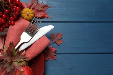 Photo of Festive table setting with autumn decor on blue wooden background, flat lay. Space for text