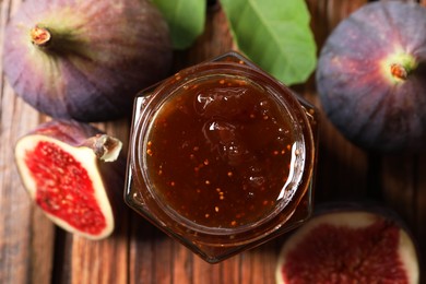 Photo of Jar of tasty sweet jam and fresh figs on wooden table, flat lay