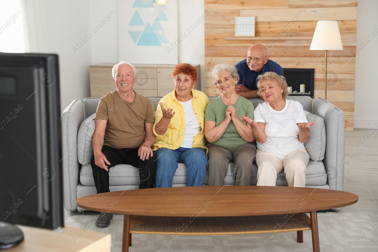 Photo of Happy elderly people watching TV together in living room