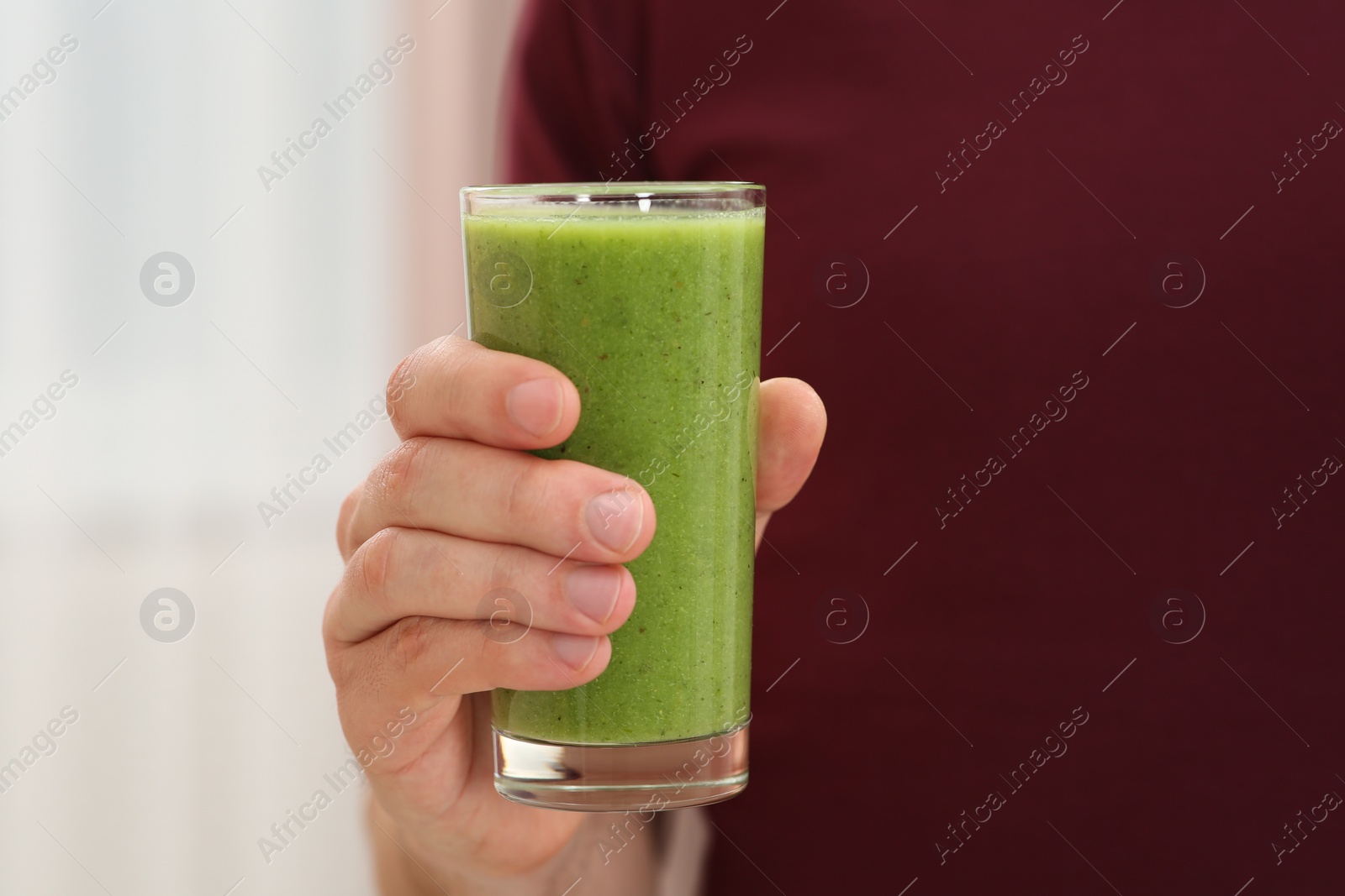 Photo of Man holding glass of delicious smoothie indoors, closeup