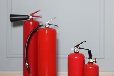 Photo of Red fire extinguishers near grey wall, selective focus