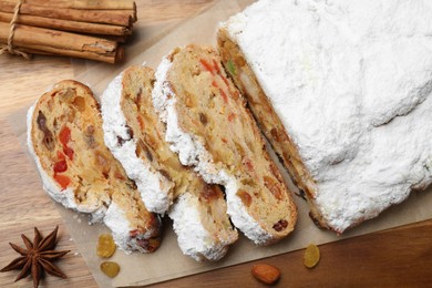 Photo of Traditional Christmas Stollen with icing sugar on wooden table, flat lay