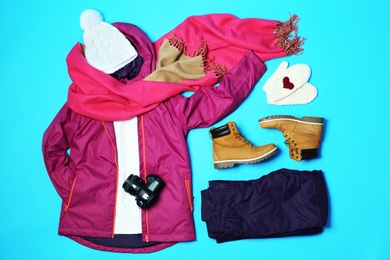 Flat lay composition with warm clothes for winter vacation on color background