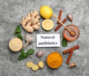 Different fresh products and card with phrase Natural Antibiotic on grey table, flat lay