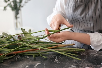 Photo of Female florist pruning stem over table, closeup