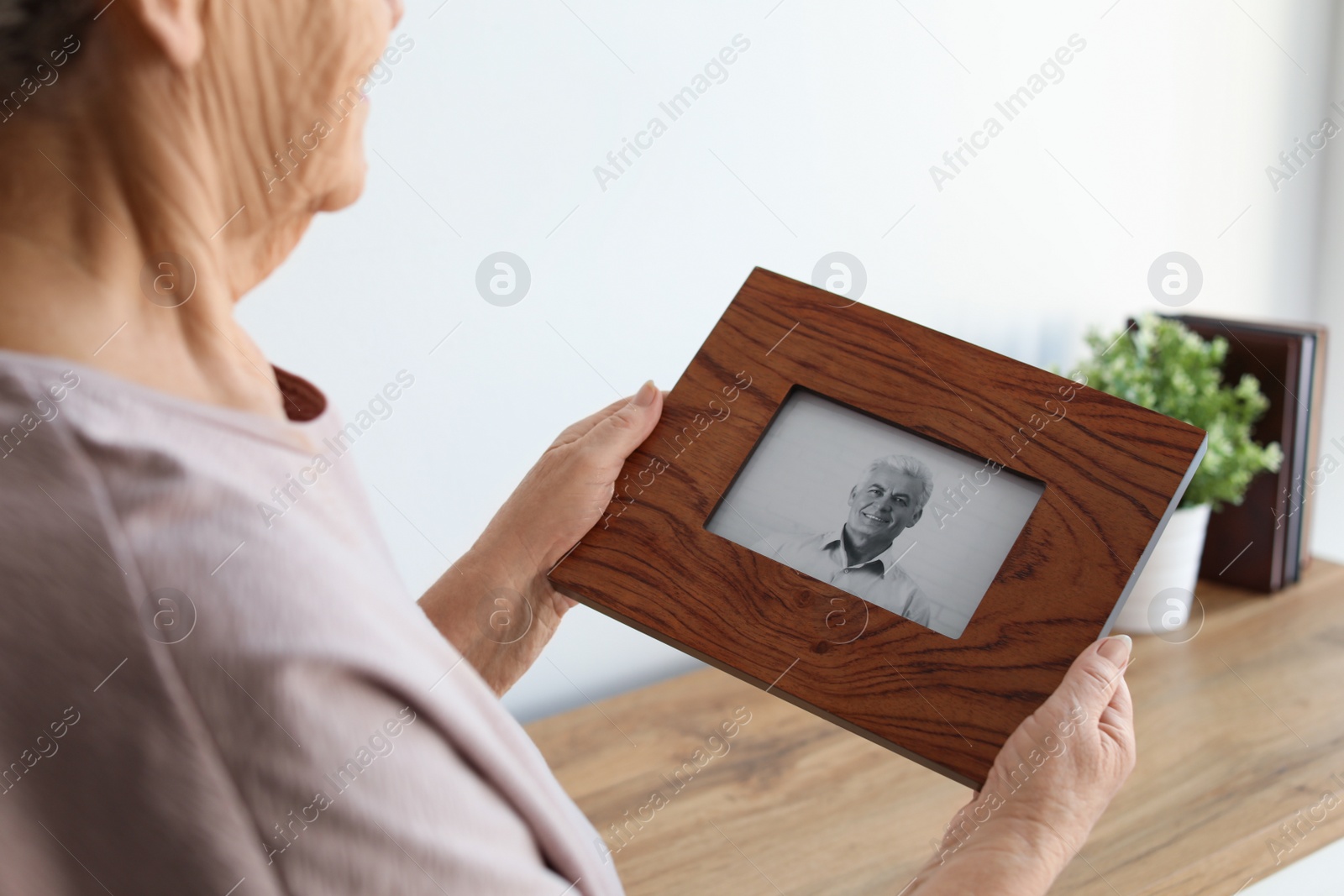 Photo of Elderly woman with framed photo of her son at home